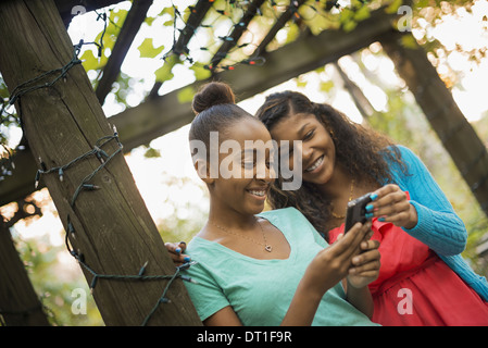 Scene di vita urbana della città di New York due ragazze in cerca di un telefono cellulare o computer pad ridere Foto Stock