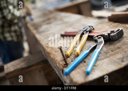 Un legname rigenerati workshop una persona in corrispondenza di un banco da lavoro e strumenti pinze e pinze allineate su un asse di legno Foto Stock