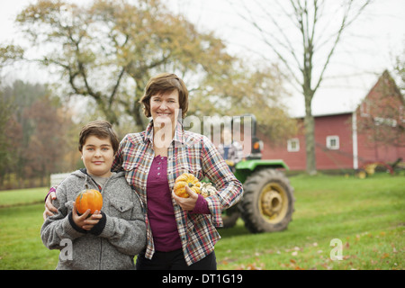 Due persone una donna e un bambino su di una azienda agricola biologica che trasportano ortaggi raccolti spremute e zucche agricoltura biologica