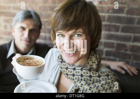 Due persone sedute in un caffè di un uomo e di una donna bianca di contenimento cina tazze di caffè cappuccino Foto Stock