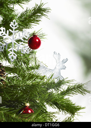 Foglia verde fogliame e decorazioni un pino ramo decorazioni di Natale due red baubles due icicle ornamenti a forma di simbolo Foto Stock