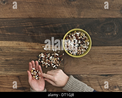 Una persona lo smistamento di diversi tipi di fagioli e legumi nelle sue mani su un tavolo di legno top Foto Stock