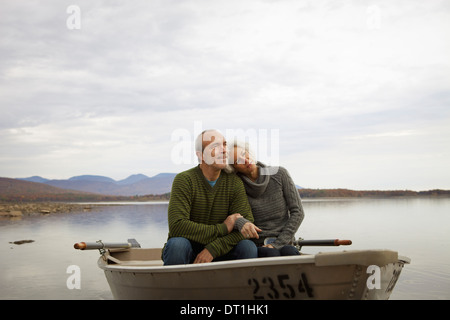 Un giovane uomo e donna seduta in una barca a remi in acqua in una giornata autunnale Foto Stock