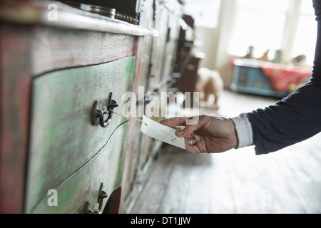 Un negozio di antiquariato in una piccola città con gli oggetti e i mobili del passato di una donna e in mano che tiene l'etichetta e il prezzo del biglietto Foto Stock