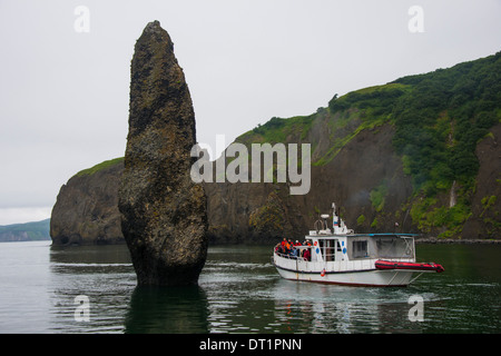 Piccola imbarcazione turistica navi accanto a un grande monolite nella baia Avacha vicino Petropavlovsk-Kamchatsky, Kamchatka, Russia, Eurasia Foto Stock