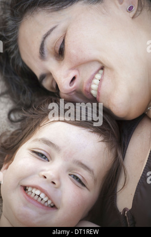Una chiusura di una madre e figlia giacente con le loro teste insieme a sorridere e ridere Foto Stock