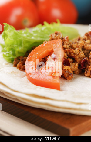 Tortilla di frumento con ingredienti per burrito sul vecchio tavolo in legno in stile rustico Foto Stock