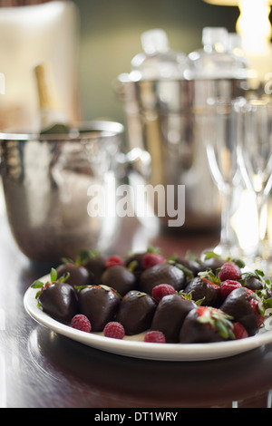 Piastra della mano-anabbaglianti fragole organica frutta artigianale in cioccolato artigianale con lampone guarnire Champagne e bicchieri Foto Stock