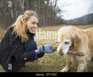 Una giovane donna all'aperto in inverno in una passeggiata con un golden retriever cane Foto Stock