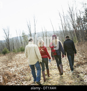 Un gruppo di quattro persone a piedi attraverso il bosco su una giornata invernale due uomini e due donne Foto Stock