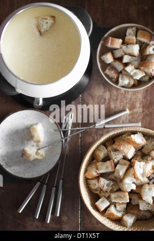 Una fondue di formaggio su un tavolo a cubetti di pane e forcelle lunghissime per intingere il pane nel ricco Formaggio fuso Miscela Foto Stock