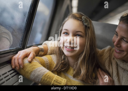 Un uomo e una giovane ragazza seduta accanto alla finestra in una carrozza del treno a guardare la campagna sorridente in emozione Foto Stock