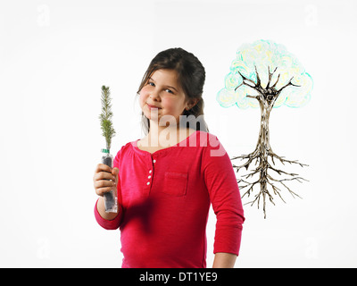 Una giovane ragazza con un piccolo albero sempreverde piantina una illustrazione di una pianta con radici disegnate su una superficie trasparente Foto Stock