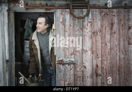 Un agriturismo biologico in Upstate New York in inverno un uomo ad un apri porta del granaio Foto Stock