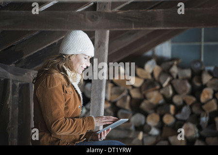 Un agriturismo biologico in Upstate New York in inverno una donna seduta in una dependance utilizzando una tavoletta digitale Foto Stock