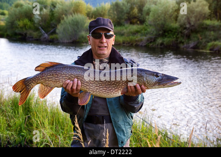 Pescatore con pesce luccio sulla riva del fiume Uur nel nord della Mongolia Foto Stock