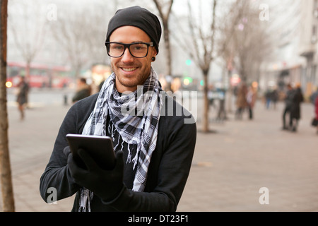 Giovane uomo la lettura dei messaggi e le informazioni utilizzando un i-pad computer tablet. Foto Stock