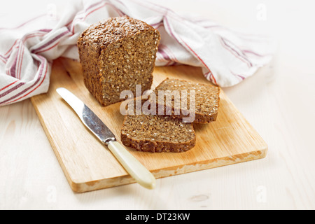 Grano intero pane con semi di girasole tagliate in pezzi sul bordo di taglio Foto Stock