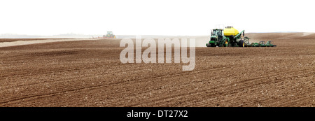 Trattori l'aratura e la semina in una fattoria campo Foto Stock