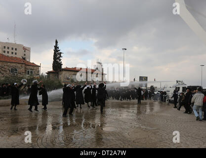 Gerusalemme. 6 febbraio, 2014. Ultra-Orthodox manifestanti ebrei vengono spruzzate dalla polizia israeliana cannone ad acqua durante una manifestazione a Gerusalemme, 6 febbraio 2014. Centinaia di ultra-ebrei ortodossi in Israele autostrade bloccato e si sono scontrati con la polizia il giovedì per protestare contro la decisione del governo di tagliare i fondi per gli studenti del seminario che evitare il servizio militare. tement. Credito: Xinhua/Alamy Live News Foto Stock