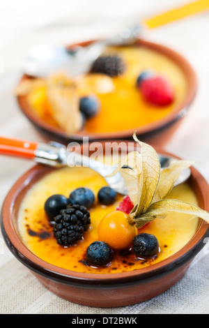 Dolce creme brulee dessert guarnita con frutti di bosco freschi Foto Stock