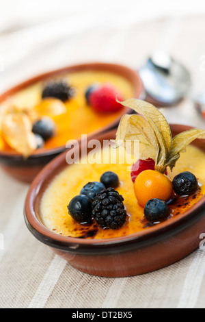 Dolce creme brulee dessert guarnita con frutti di bosco freschi Foto Stock