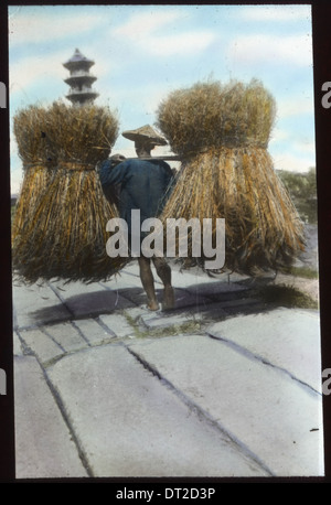 Uomo che porta due grandi fasci di paglia, Cina, ca.1917-1923 (IMP-YDS-RG224-OV1- Foto Stock