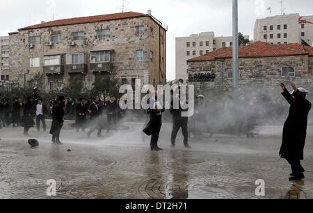 Gerusalemme. 6 febbraio, 2014. Ultra-Orthodox manifestanti ebrei vengono spruzzate dalla polizia israeliana cannone ad acqua durante una manifestazione a Gerusalemme, 6 febbraio 2014. Centinaia di ultra-ebrei ortodossi in Israele autostrade bloccato e si sono scontrati con la polizia il giovedì per protestare contro la decisione del governo di tagliare i fondi per gli studenti del seminario che evitare il servizio militare. Credito: Xinhua/Alamy Live News Foto Stock