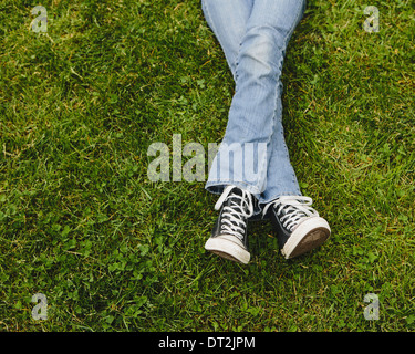 Dieci anni di ragazza distesa sull'erba gambe incrociate a livello delle caviglie Foto Stock