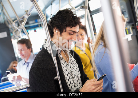 New York City Park persone uomini e donne su un autobus del trasporto pubblico mantenendo in contatto un giovane uomo di controllare il suo telefono cellulare Foto Stock