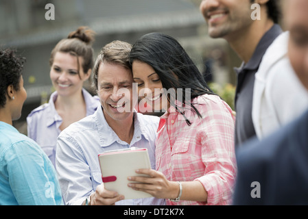 La gente all'esterno Primavera tempo di New York City un paio nel centro guardando una tavoletta digitale schermo Foto Stock