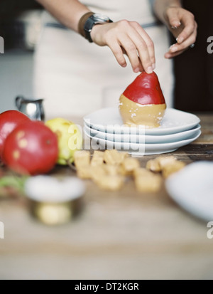 Una donna in una cucina domestica cucina fresca di immersione pere biologiche in una salsa per dessert freschi ingredienti marrone cubetti di zucchero Foto Stock