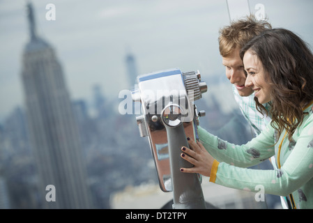 Vista su cityA coppia giovane guardando attraverso il telescopio Foto Stock