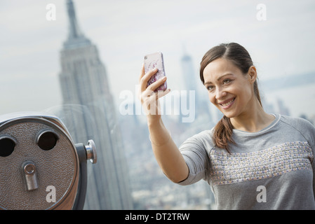 Vista su cityA donna con il suo smart phone per scattare una fotografia Foto Stock