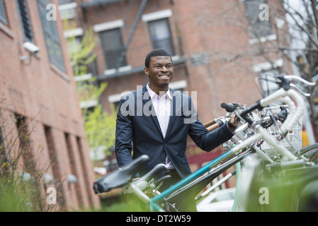 Vista su cityA uomo in una tuta blu da una rastrelliera per biciclette in un parco della città Foto Stock