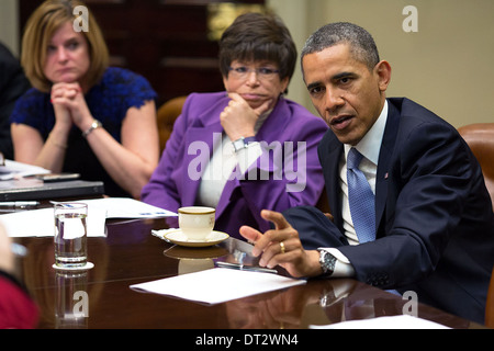 Il Presidente Usa Barack Obama gesti durante un incontro con i consulenti nella sala Roosevelt della Casa Bianca Dicembre 18, 2013 a Washington, DC. Seduti accanto al Presidente sono Communications Director Jennifer Palmieri, sinistra e Senior Advisor Valerie Jarrett. Foto Stock