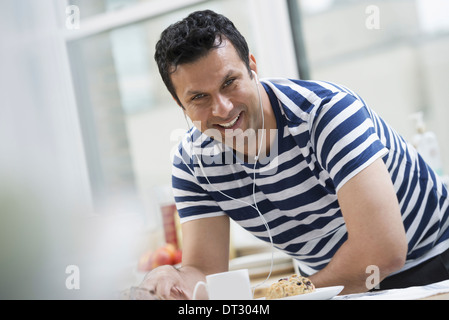 In un ufficio o un interno dell appartamento a New York City un uomo in striped tee shirt appoggiata al bar per la prima colazione Foto Stock