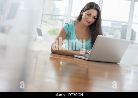 Una giovane donna comodamente seduto in una tranquilla arioso ambiente office Foto Stock