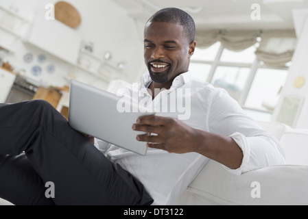 Una persona comodamente seduto in una tranquilla arioso ambiente office utilizzando una tavoletta digitale Foto Stock
