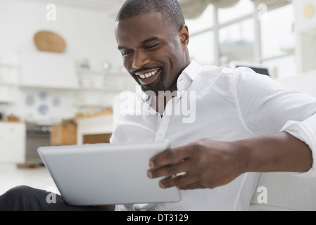 Una persona comodamente seduto in una tranquilla arioso ambiente office utilizzando una tavoletta digitale Foto Stock