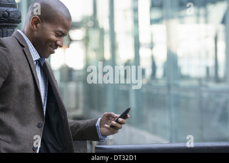 Un uomo in piedi all'aperto controllando il suo telefono cellulare Foto Stock