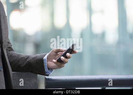 Un uomo in piedi all'aperto controllando il suo telefono cellulare Foto Stock