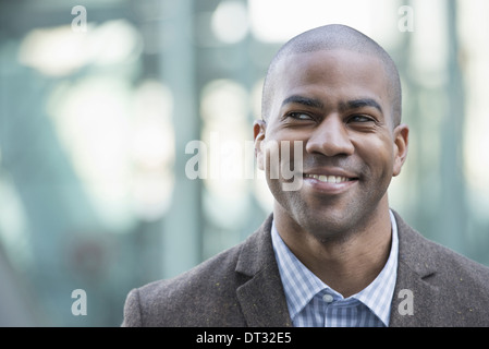 Un uomo in giacca e cravatta sorridendo e guardando in lontananza Foto Stock