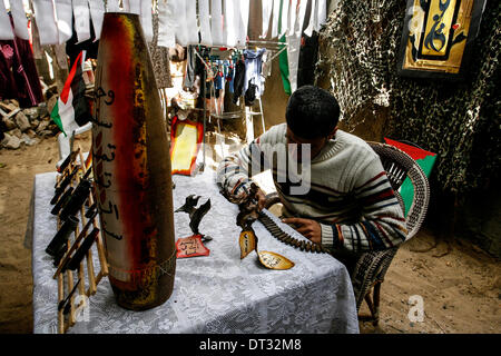 La striscia di Gaza, Territori palestinesi. 6 febbraio, 2014. Palestinesi Mohammed al-Zomar, che dipinge su resti di munizioni israeliane, visualizza un pezzo della sua opera presso il suo studio di Bureij Refugee Camp nella zona centrale della striscia di Gaza il 6 febbraio 2014. Al-Zomar disegna e vernici su resti di munizioni israeliana che ha raccolto durante il 2008-2009 Israele tre settimane di offensiva a Gaza e durante otto giorni di conflitto nel 2012. Le parole arabe sul missile (R) leggi " Quando un fiore svanisce, un migliaio di salire. © Abed Rahim Khatib/NurPhoto/ZUMAPRESS.com/Alamy Live News Foto Stock