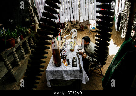 La striscia di Gaza, Territori palestinesi. 6 febbraio, 2014. Palestinesi Mohammed al-Zomar, che dipinge su resti di munizioni israeliane, visualizza un pezzo della sua opera presso il suo studio di Bureij Refugee Camp nella zona centrale della striscia di Gaza il 6 febbraio 2014. Al-Zomar disegna e vernici su resti di munizioni israeliana che ha raccolto durante il 2008-2009 Israele tre settimane di offensiva a Gaza e durante otto giorni di conflitto nel 2012. Le parole arabe sul missile (R) leggi " Quando un fiore svanisce, un migliaio di salire. © Abed Rahim Khatib/NurPhoto/ZUMAPRESS.com/Alamy Live News Foto Stock