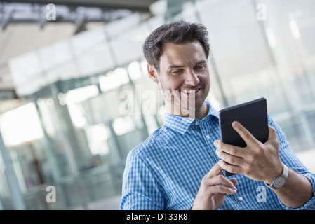 Un Uomo in camicia blu utilizzando una tavoletta digitale Foto Stock