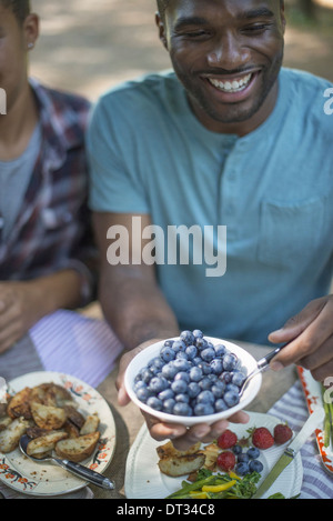 Uomo con una ciotola di mirtilli freschi Foto Stock