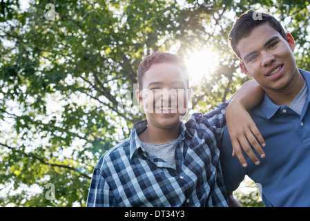 Due giovani uomini all'aperto uno con il suo braccio intorno alle spalle dell'altro Foto Stock