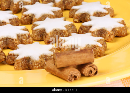 La cannella star cookies (in tedesco Zimtsterne), tipico tedesco e svizzero di biscotti di Natale su una piastra di colore giallo. Foto Stock