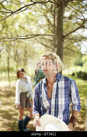 Un gruppo di amici a piedi verso il basso di un viale di alberi nel bosco Foto Stock